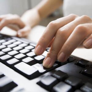 A female typing on a black computer keyboard