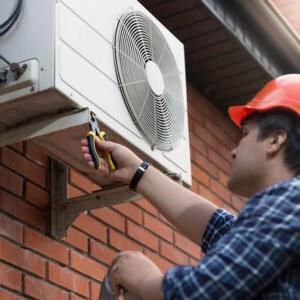 A man connecting an outdoor air conditioning unit